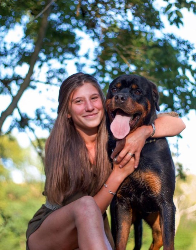 Chien rottweiler assis à coté de sa maitresse.